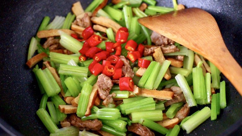 豆干肉片芹菜小炒,打开锅盖,加入焯过水的芹菜和小红尖椒丁。
