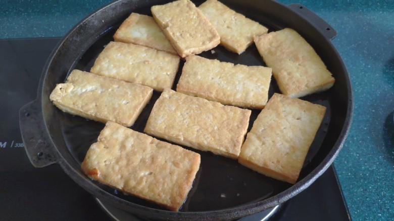 铁板豆腐,等到豆腐一面煎黄后,给它翻个儿面继续煎。