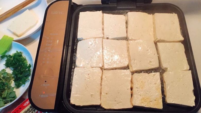 铁板豆腐,将豆腐从盐水里捞出,用厨房纸吸干水份。
油热之后把豆腐片一块块摆上去,
在豆腐表面继续刷一层油。