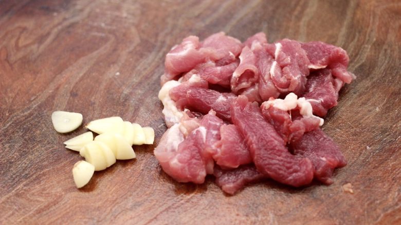 黄瓜双椒炒肉便当,把猪肉洗净后,用刀切成薄片,<a style='color:red;display:inline-block;' href='/shicai/ 2794'>大蒜</a>去皮后,用刀切成薄片。