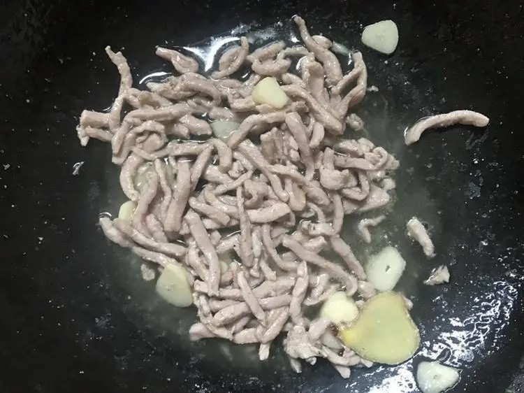 豆干炒芹菜,锅里放入适量的油,油肉后放入蒜片,姜片,放入肉丝翻炒到变色。