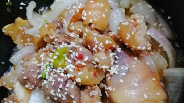 秘制猪脚,砂锅里面准备洋葱垫底,把猪蹄和猪脚汤倒入砂锅,撒上芝麻,