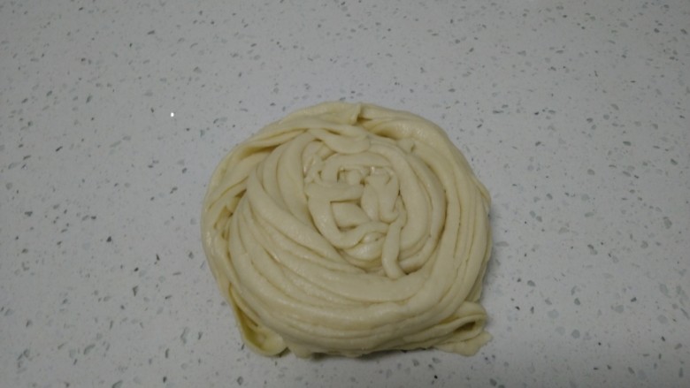 千丝万缕烫面饼,拉住两头抻长,从一头卷起,底部压在下面。