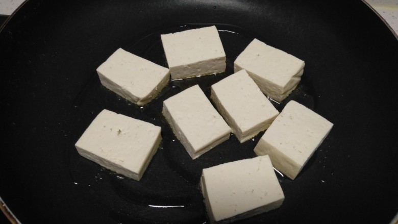 酱炒豆腐、素肠、小西芹,不粘锅中放入少许油,中火煎至一面金黄。