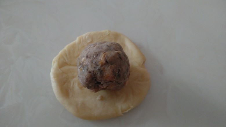 江豆蛋黄酥,用手将两头向中间收起,再用手压扁,再用擀面杖擀成薄片,放入包好咸蛋黄的豆沙团。