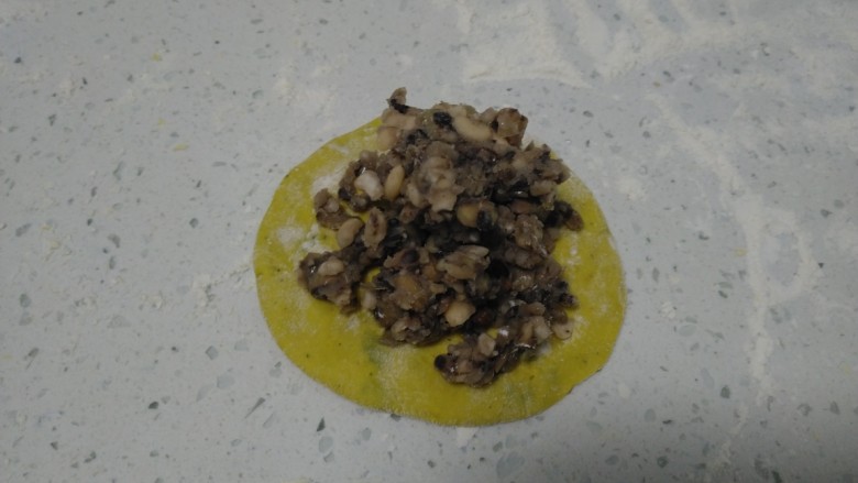 南瓜豆沙包,取一个剂子用手压扁,包入豆沙。