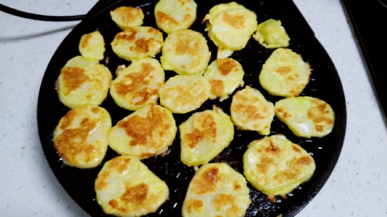 土豆、鸡蛋椒盐小饼,电饼铛均匀涂上食用油,放入土豆片,煎至一面金黄。