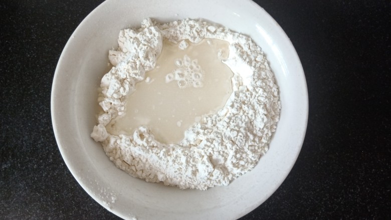 玉米秋叶煎饺,接着擀皮。将200克中粉倒入盆中，中间加入95克水