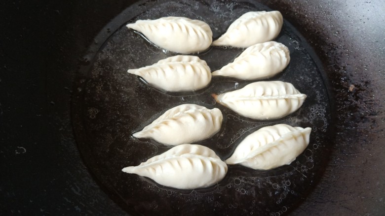 玉米秋叶煎饺,锅里热少许油，放入秋叶饺子煎，煎至地面金黄，再加水，水大约没过饺子一半。待水收干。