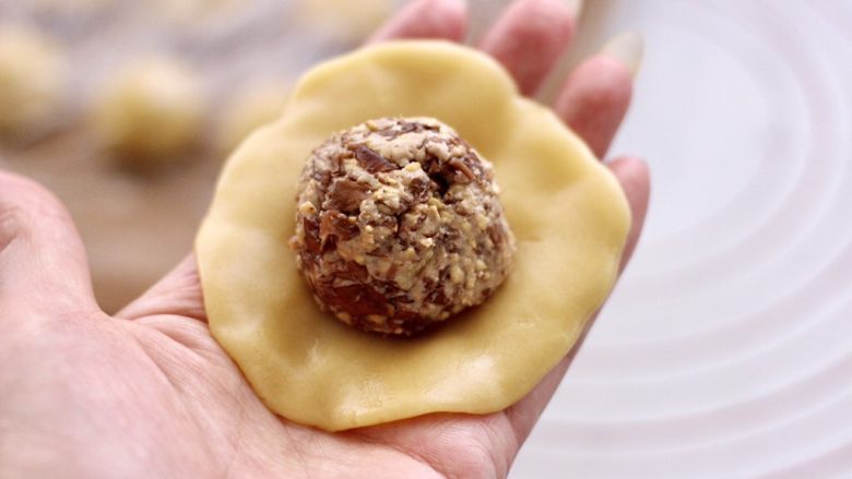 玫瑰花干果饼,取一个剂子用手摁扁后,放入馅料。
