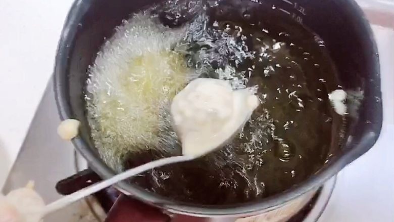 土豆虾球(天妇罗土豆虾球),油锅烧至5成热,用勺子挖出虾球,逐一放入到油锅中。