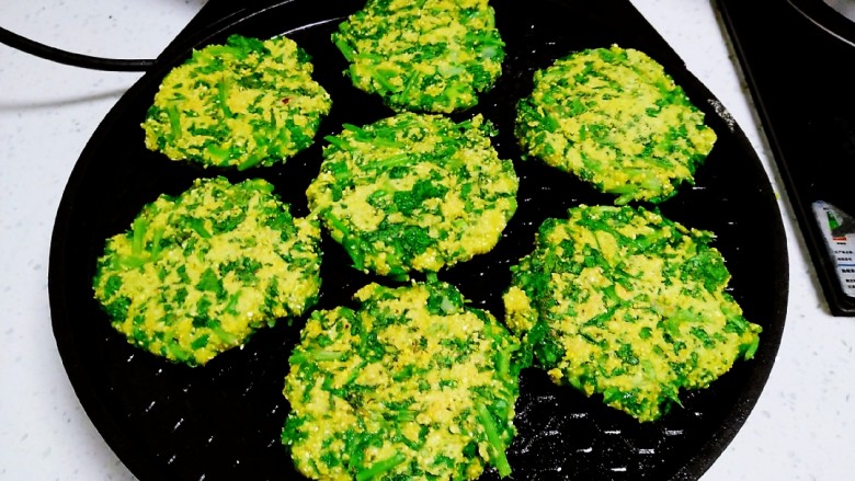 小白菜、玉米面、鸡蛋饼,电饼铛预热后均匀涂上食用油,用手将菜团团圆,放入电饼铛中。