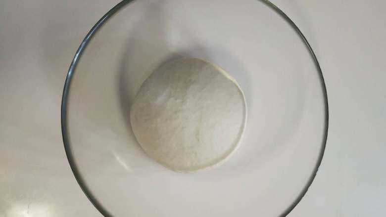 北海道牛奶土司,３、揉成光滑的面团后放入容器内，盖保鲜膜放入冰箱冷藏发酵１８个小时 。一般头一天晚上做好。
