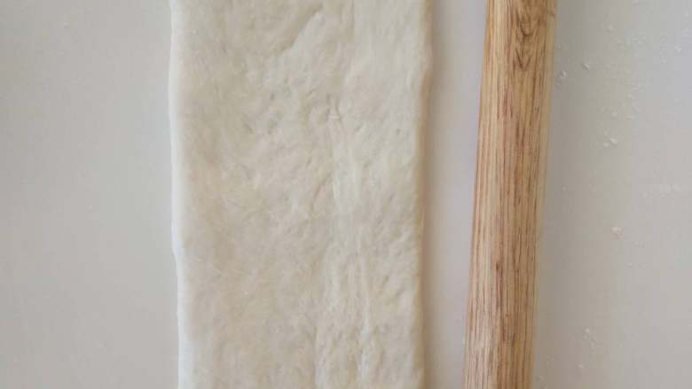 北海道牛奶土司,１３、将松弛好的面团擀开，翻面，压薄底边，长度与擀面杖差不多长就可以。
