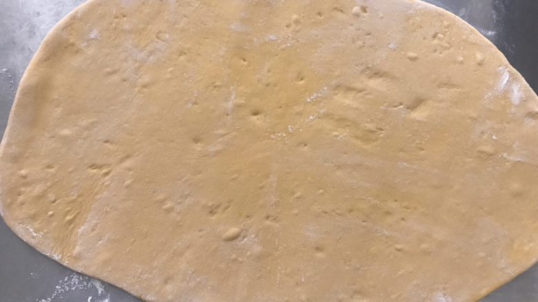 南瓜花卷,案板上撒点面粉,防止擀好的面皮粘在案板上。把面团擀开,擀成0.5厘米厚的面片。在面团两面撒一些干粉防粘