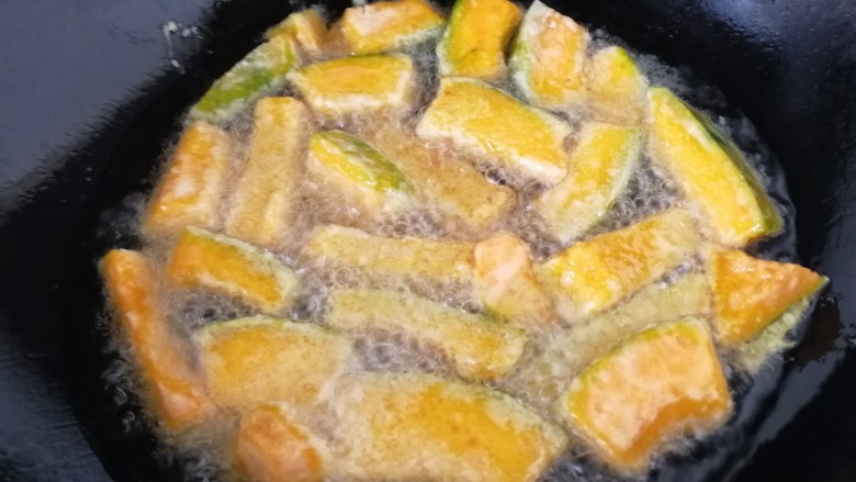 蛋黄焗南瓜,油温6-7成热时,中火,一个一个的把南瓜条放入油里。炸3分钟。