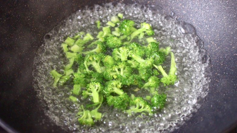 苹果北极虾时蔬炒饭,锅中倒入适量的清水烧开后,倒入少许盐和几滴花生油,把西兰花进行焯水,看见西兰花变色断生,捞出过冷水后沥干水分。