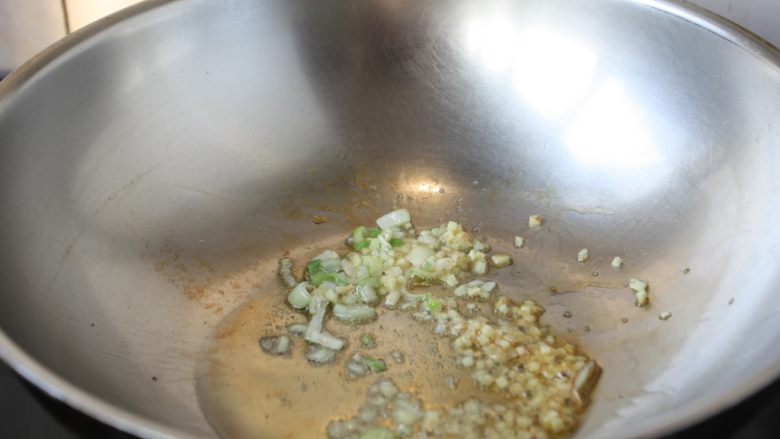 鸡米炒毛豆,热锅凉油,放入葱花蒜末炒出香味。