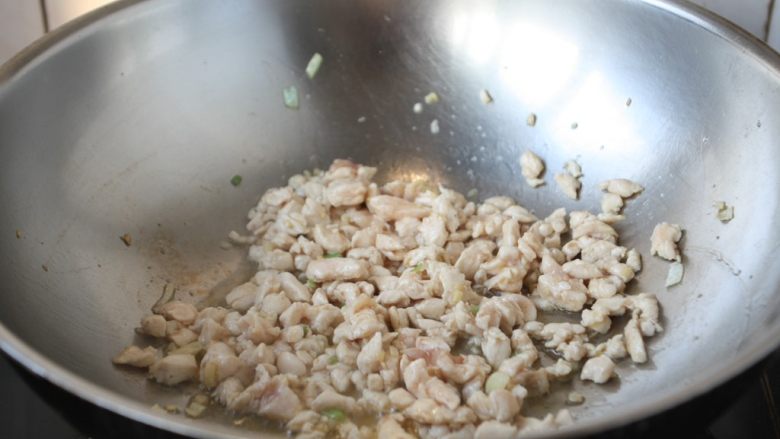 鸡米炒毛豆,放入鸡肉丁,翻炒至变色。