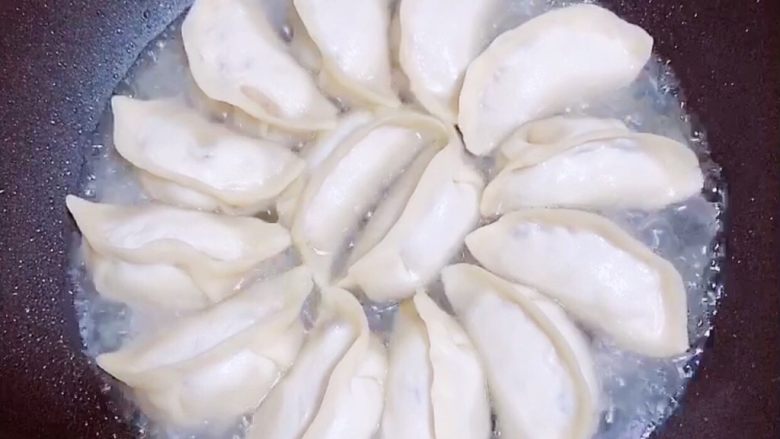 鸡蛋抱饺,大火烧开水后,转至小火。盖盖儿煎熟饺子。
