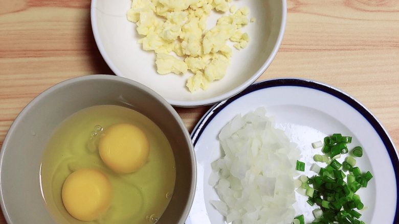 鸡蛋抱饺,煎饺子时,准备其他食材,将洋葱、小葱切碎备用。鸡蛋打入碗中。