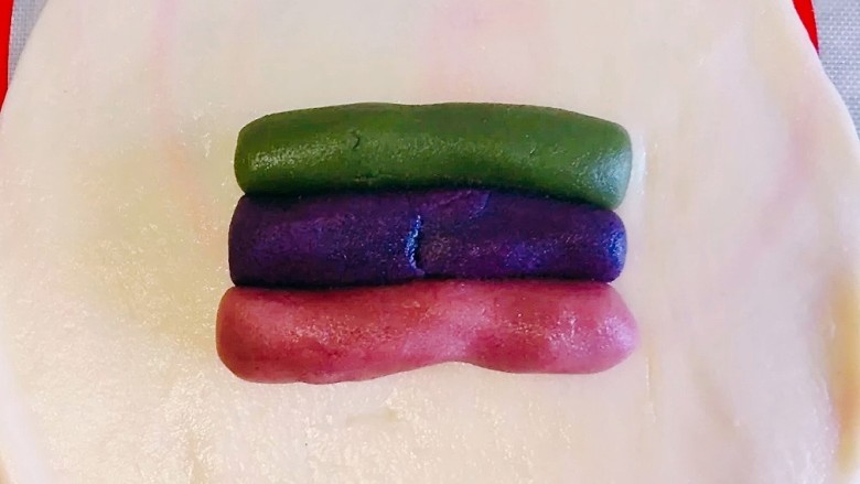 彩虹蛋黄酥,一份水油皮,用手掌压扁之后,用擀面杖擀开,把三色的油酥放上去