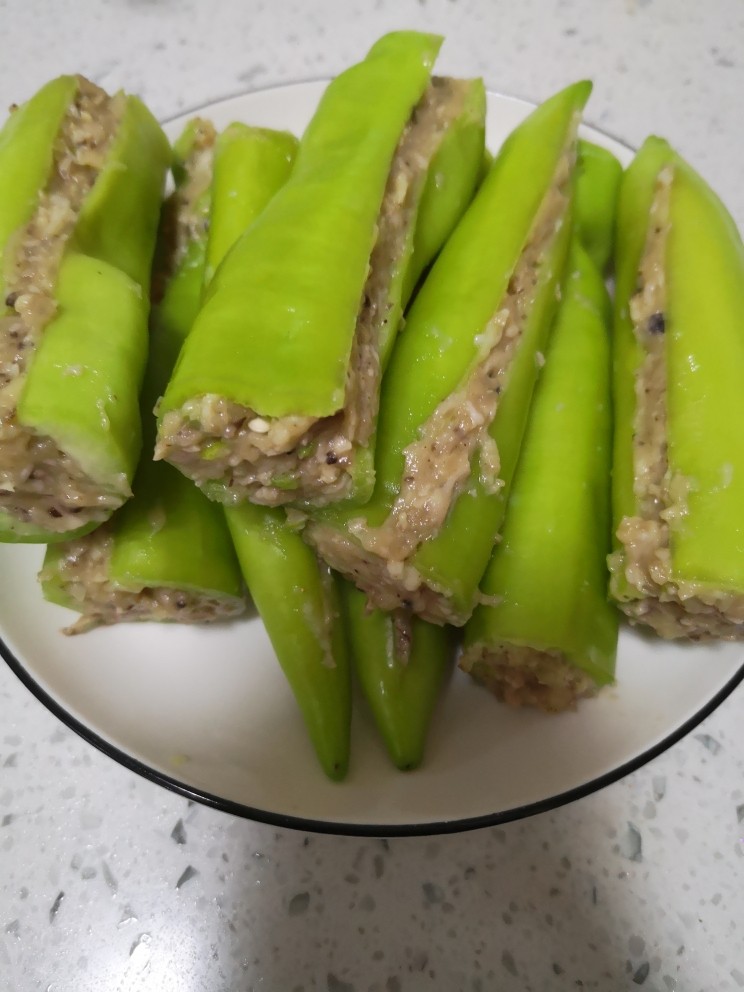青椒酿肉,肉馅塞进青椒里面,塞好肉馅把青椒一合,刮掉多余的肉馅,只要青椒里面塞的够贴合,不用太满
