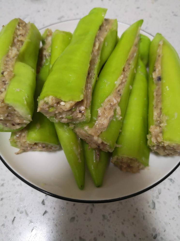 青椒酿肉,肉馅塞进青椒里面，塞好肉馅把青椒一合，刮掉多余的肉馅，只要青椒里面塞的够贴合，不用太满