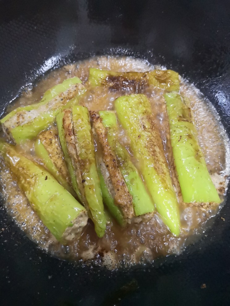 青椒酿肉,倒入调好的料酒,盖锅盖大火烧开,转小火十分钟