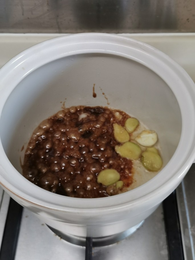 十年陈皮扣肉(回味无穷),沙锅烧热,落小许食用油,放入片糖和姜蒜,糖融化,姜蒜爆香。