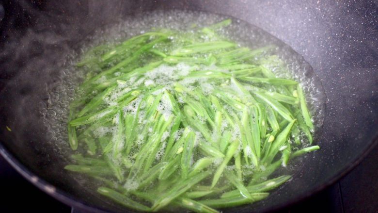 香肠辣爆芸豆丝,锅中倒入适量的清水煮沸后,放入芸豆进行焯水,看见芸豆丝变色变软时,捞出过冷水后沥干。