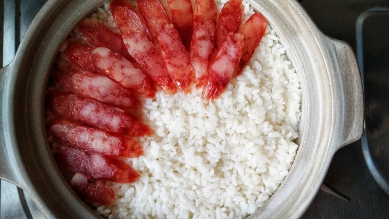 腊味煲仔饭,再将腊味铺在米上,因为这样腊肠的咸度会更低一些,然后再煮5分钟,在煲煮的过程中,米饭会自动吸收腊味的精华,米饭被肉香包裹,才是煲仔饭的正道。