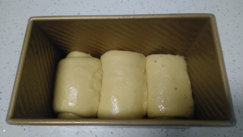 手撕面包,模具均匀涂上食用油,模具底部撒上芝麻,放入面包生胚。