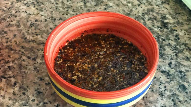 麻辣拌面,过滤掉油里的香料,把油倒入辣椒粉中,用勺子拌匀。