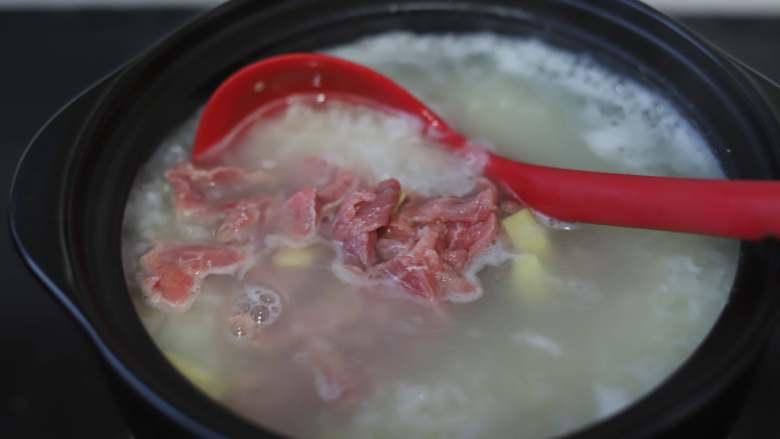 藜麦牛肉粥,大约20来分钟粥里的米就煮开花了,如果喜欢浓稠一些的可以再多煮一会儿,达到自己需要的程度后就可以下牛肉进去了,牛肉放进去的同时加入一些姜丝,御寒又去腥味,同时加入一勺玉米油,其它无色无味的油也可以,用汤勺搅动大米,让粥变得粘稠,这一步在商业煮粥的过程中叫“搅稠”,多加这一步,牛肉粥会更加顺滑,口感也会特别滑嫩。