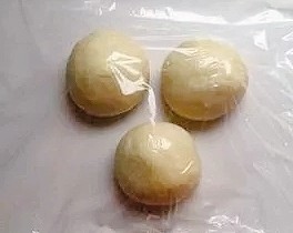 紫米面包,把面团在面板上按揉几下,排出气体。均匀的分成3份滚圆,盖上保鲜膜松弛20分钟