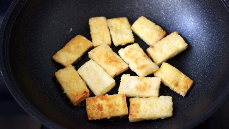 照烧北豆腐,看见一面煎至金黄色后,再把另一面也煎制金黄色的时候。