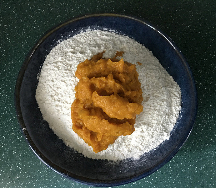 南瓜豆沙馒头,接着将南瓜泥分次加入面粉中,边加边用筷子搅成絮絮状