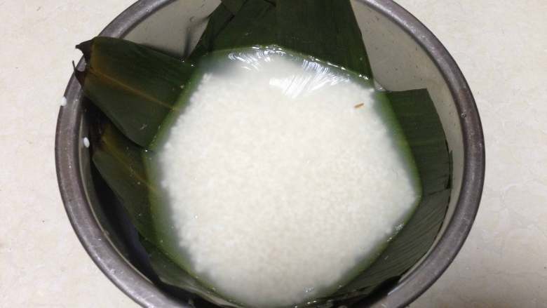 糯米南瓜盅,容器底部铺上粽子叶,倒入洗好的糯米和300克清水,没有粽子叶的可以不放