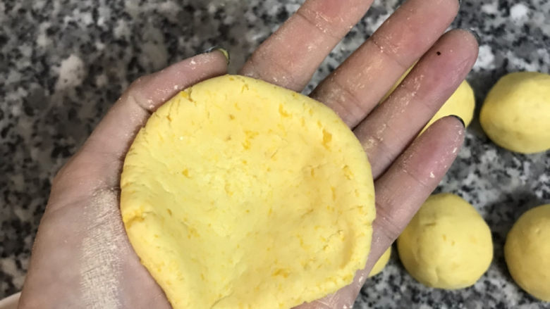 南瓜芝麻饼,将南瓜面团压扁中间有凹槽;