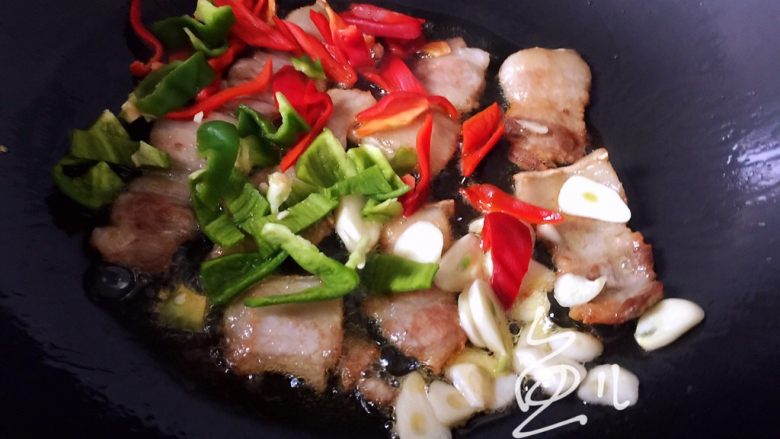 杏鲍菇炒肉片,肉片变色后,放入青红椒和蒜片翻炒均匀