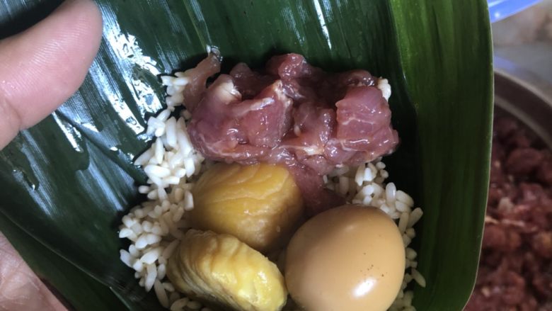 板栗猪肉鹌鹑蛋粽子,按照“糯米-板栗猪肉鹌鹑蛋-糯米”的顺序放入竹叶中包好,绑上绳子。不要绑太松,煮的时候才不会散开。