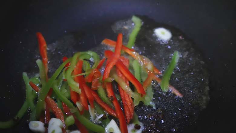炝炒莲藕,油锅烧热,下入蒜片,花椒,青红椒炒出香味。