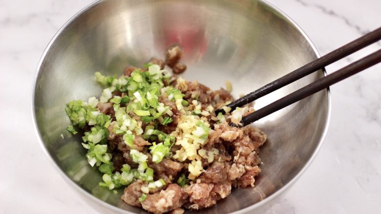 四喜饺子,把猪肉馅顺时针方向搅拌均匀后,加入切碎的葱<a style='color:red;display:inline-block;' href='/shicai/ 37'>姜</a>末。