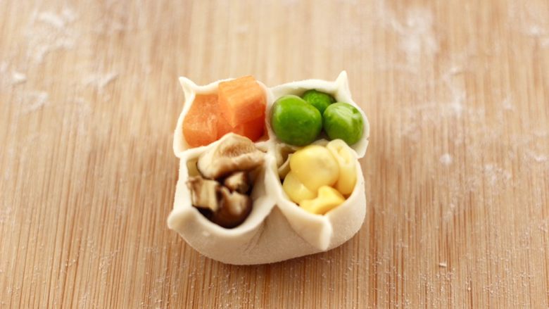 四喜饺子,把胡萝卜、玉米粒、青豆和香菇丁,依次放入点缀。
