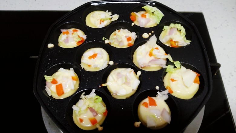 鱿鱼小丸子,把模具放在煤气罩上，待模具均匀受热，均匀涂上食用油，倒入8分满的面糊，迅速放入鱿鱼、包菜、白菜、胡萝卜