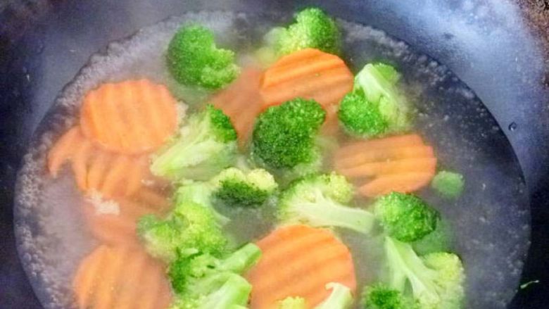 美味的新奥尔良煎鸡肉饭,锅中放入一点香油和一勺盐,水开放入胡萝卜开锅后在放入西兰花焯水。