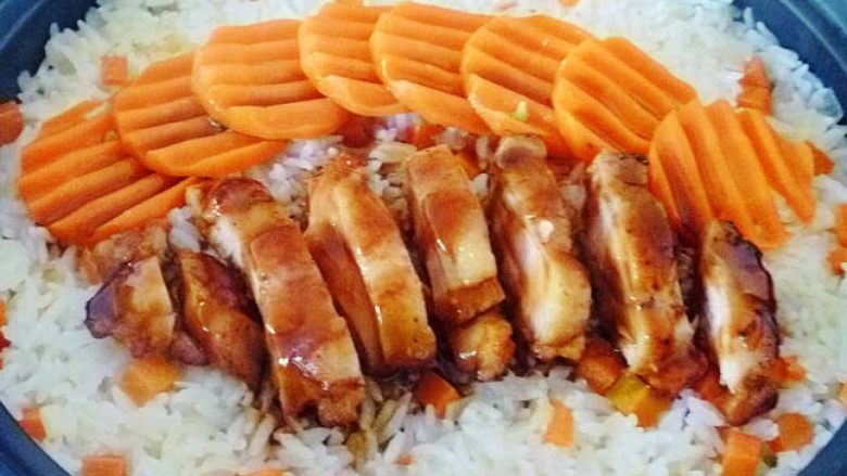 美味的新奥尔良煎鸡肉饭, 等米饭已经熟了,打开把胡萝卜片和鸡肉码在米饭上,淋上一半的料汁在焖2分钟左右。