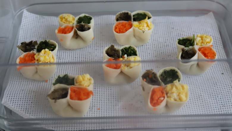 虾仁四喜饺子,分别往每个饺子的圆洞里填入胡萝卜碎,荠菜碎,木耳碎和鸡蛋碎,填的时候可以用一个小点的勺子装馅,比用筷子方便。