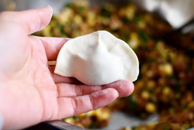 玉米猪肉馅饺子,放入饺子馅后,折起来两手拇指一压,饺子就做好了;
